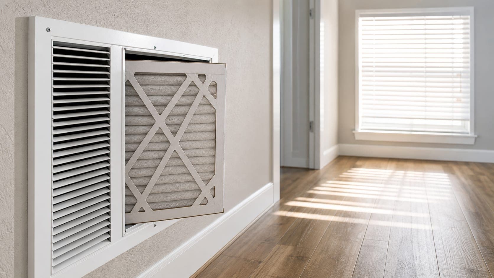 Clean HVAC filter being replaced in a home hallway to support lower cooling energy use.
